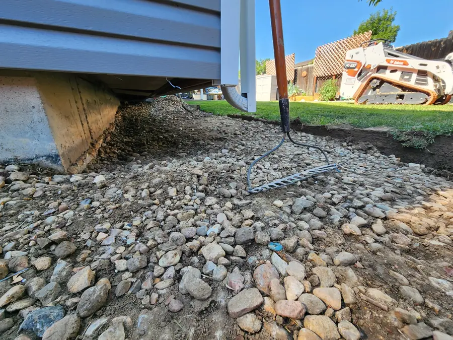 A river-rock drainage bed along the side of a house