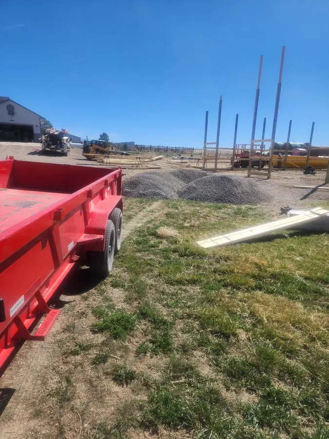 A red dump trailer on a new construction site with gravel piles and utility poles